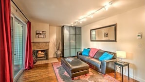 A modern living room with a fireplace, a sofa with colorful cushions, a coffee table, and a large mirror on the wall.