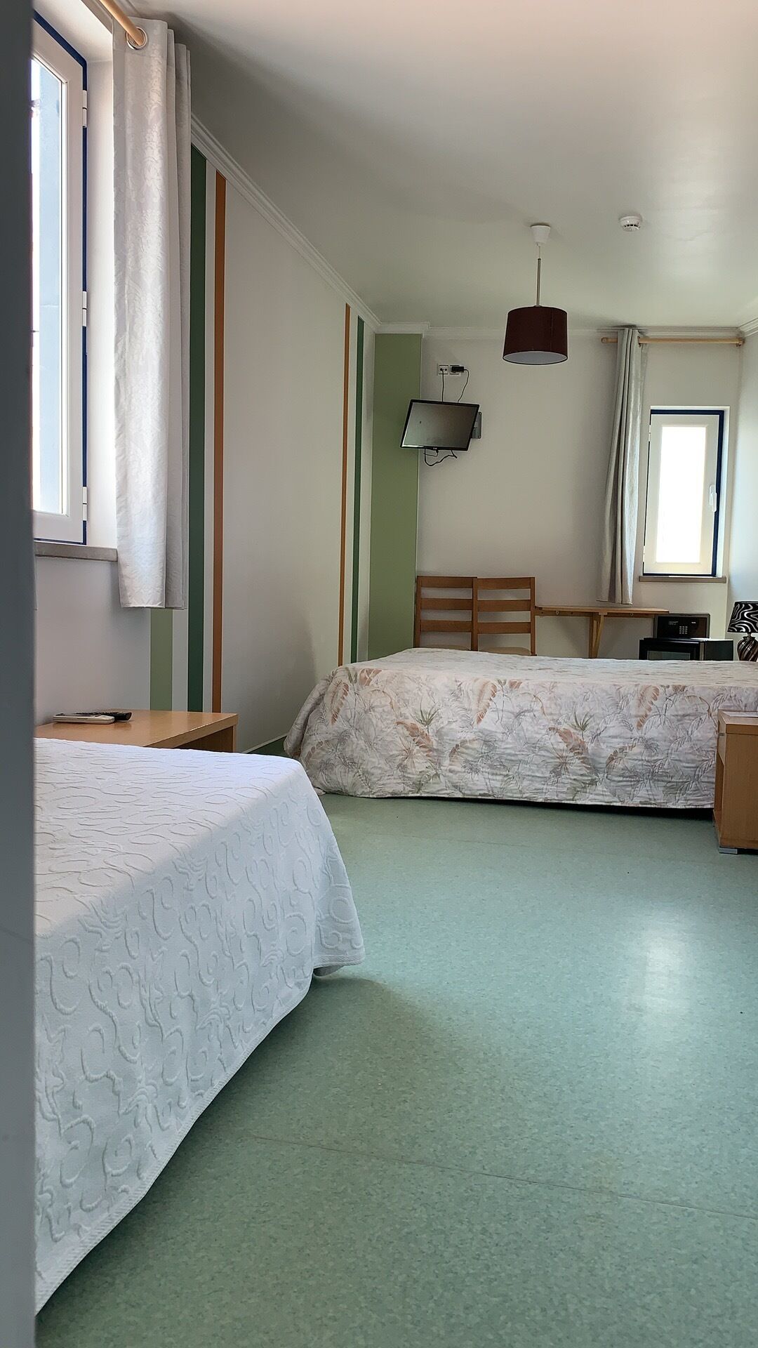 Un dormitorio con dos camas, un escritorio, una silla, una lámpara y un televisor.