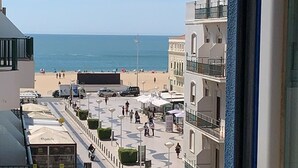 A coastal street with buildings, a beach, and parked cars. - WEAA Hotel (Nazaré)