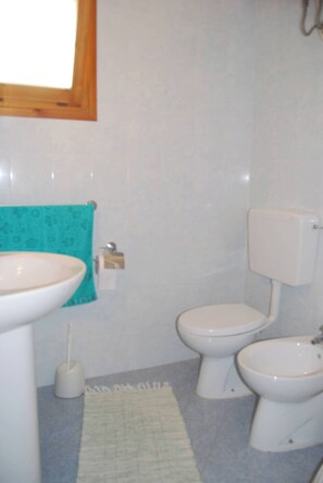 Une salle de bain équipée d’un lavabo, de toilettes, d’un bidet et d’une fenêtre.