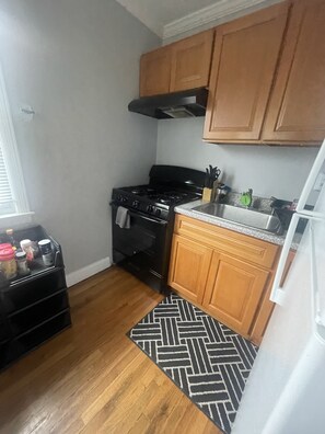 Una cocina funcional con armarios de madera, estufa negra y alfombra estampada.