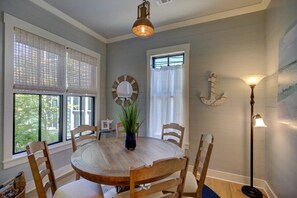 A dining area with a round wooden table, four chairs, a potted plant, and a wall-mounted decorative piece.