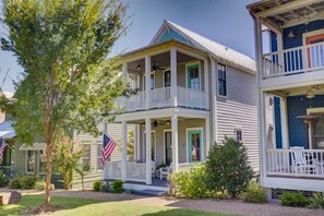 A two-story house with a porch, a flag, and a small tree. - Watercolor Cottage (Carlton Landing)
