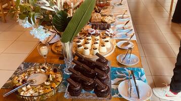 Una mesa de buffet con distintos alimentos, un florero con flores y una mesa de madera.