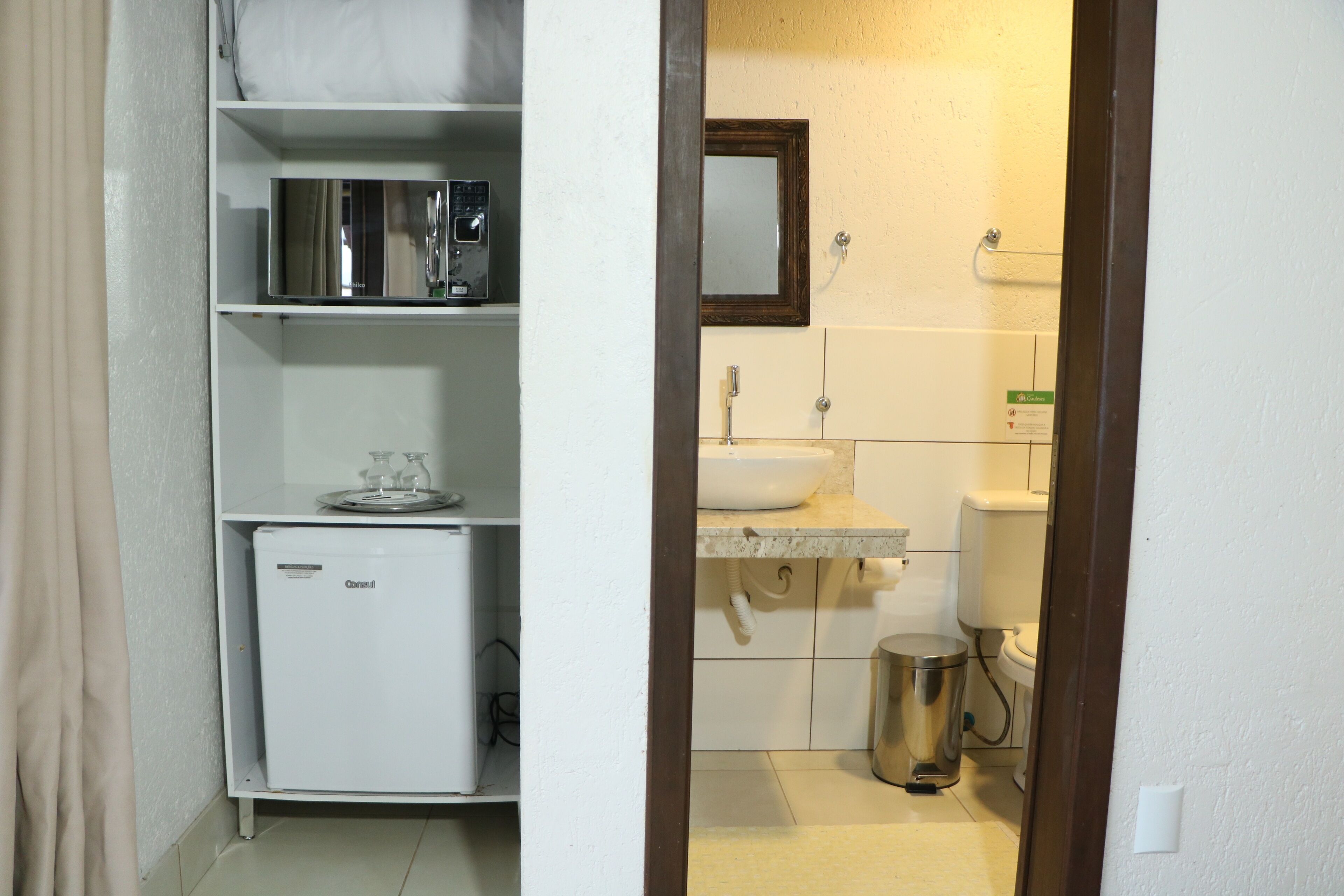 Une salle de bain compacte comprenant un lavabo, des toilettes et un petit réfrigérateur.