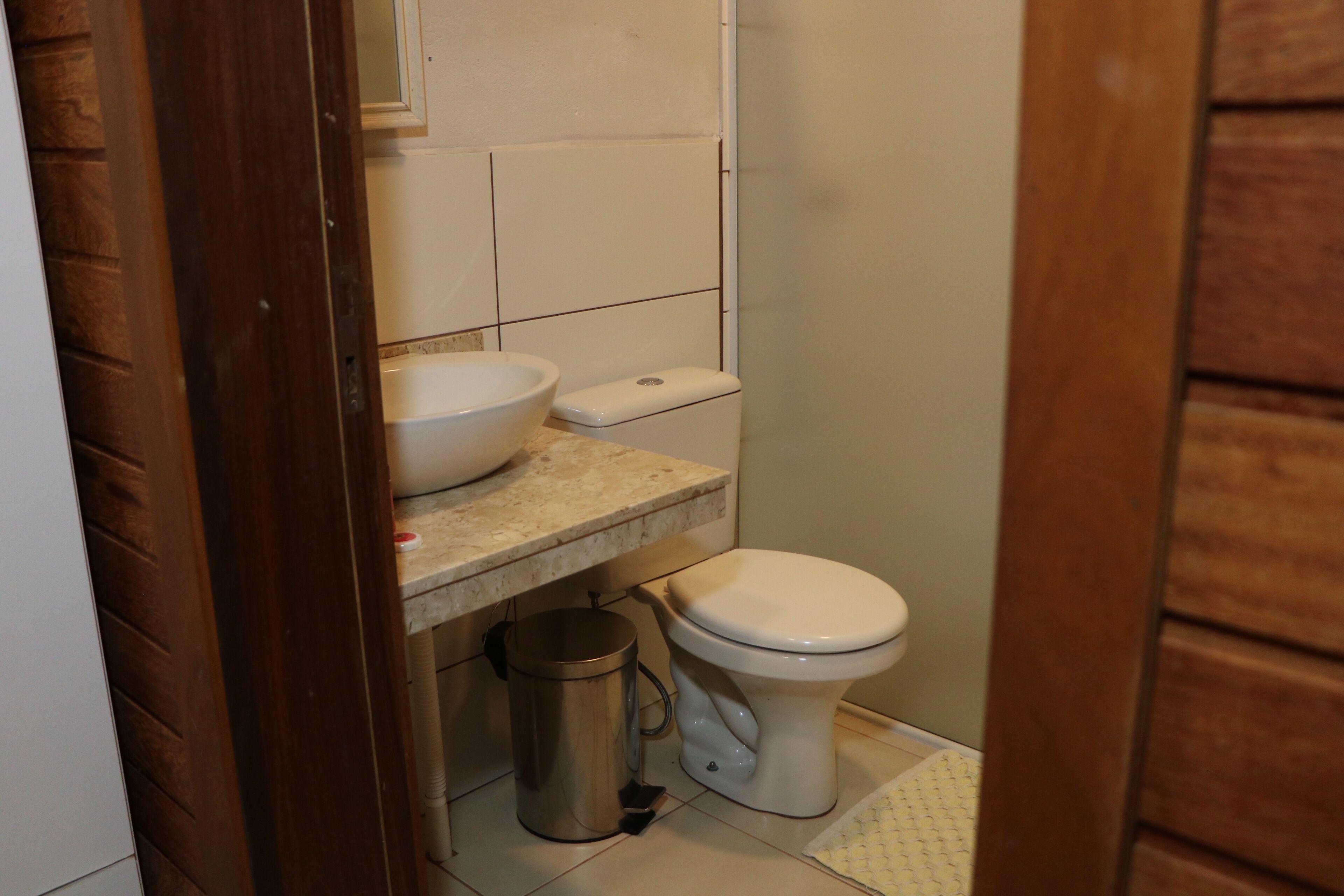 A small bathroom with a toilet, sink, and trash can.