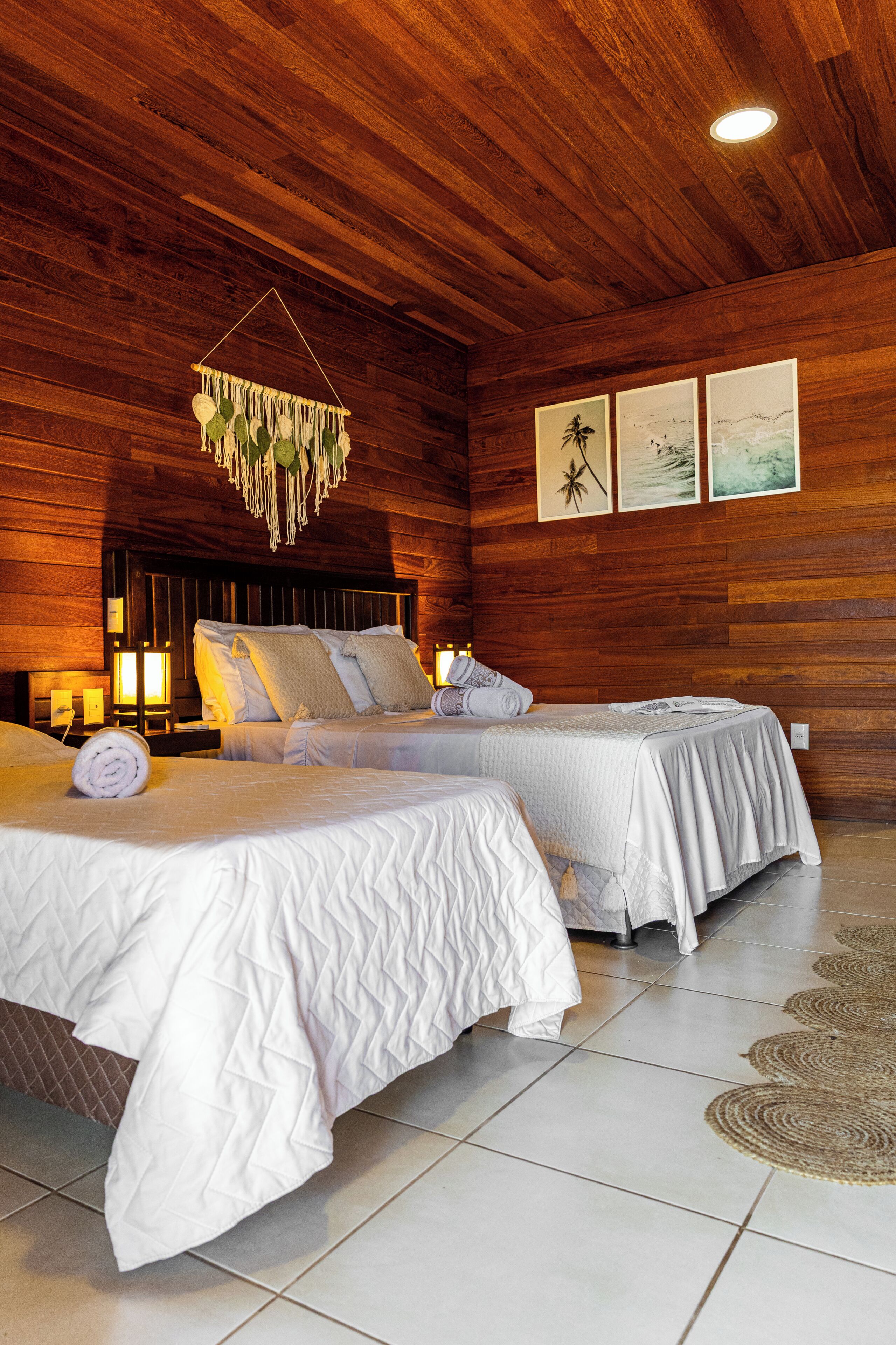Een kamer met houten lambrisering, twee bedden, een hanglamp en lijstwerken aan de muur.