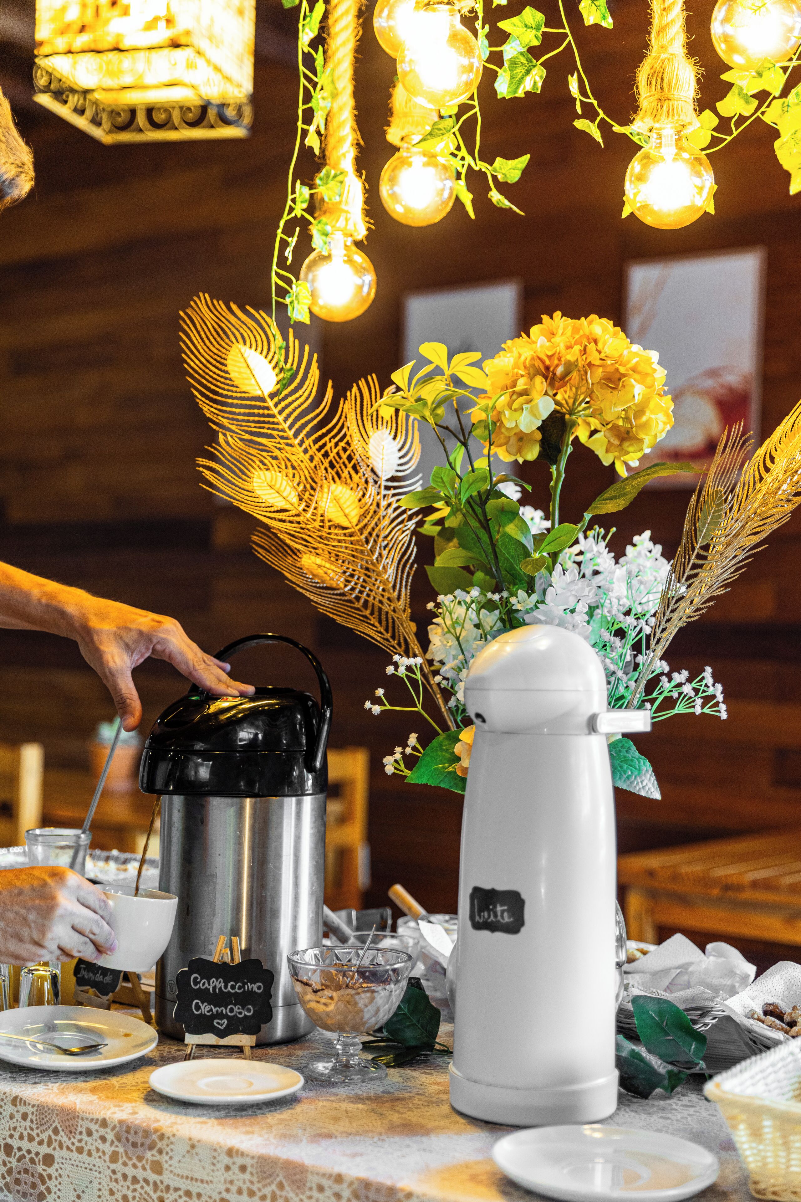 A coffee station with a coffee maker, a milk frother, and a sign indicating a cappuccino and latte.
