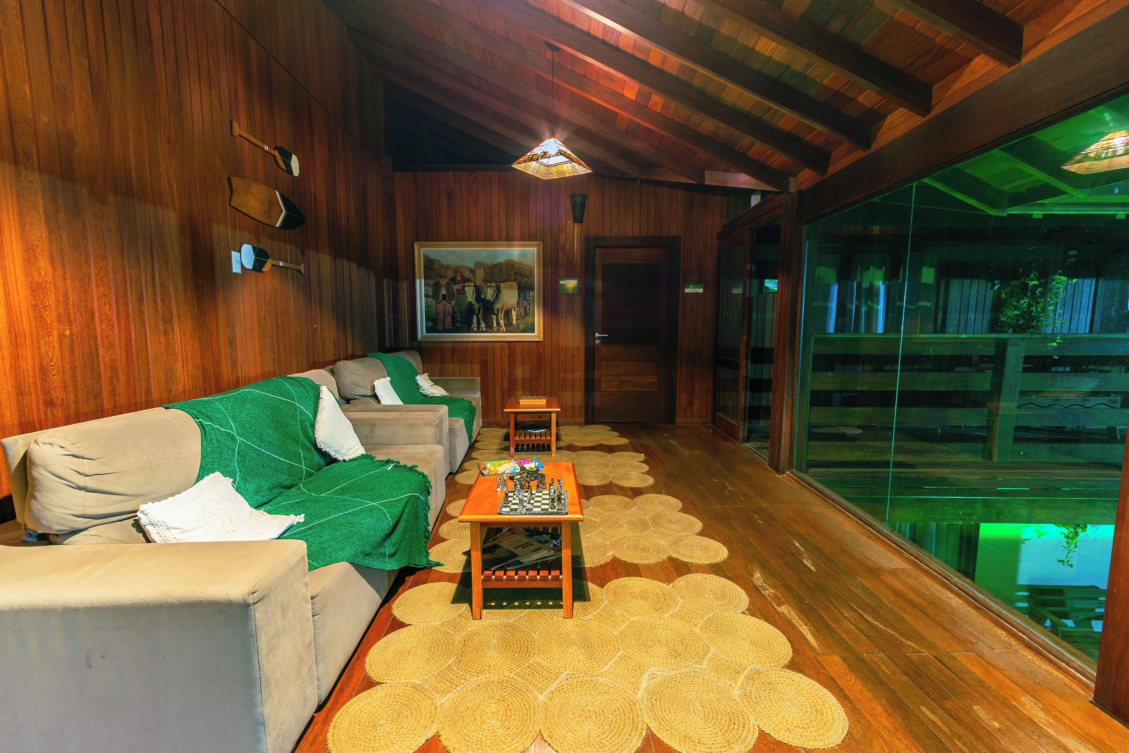 A wooden-floored room with a sofa, a chess table, and a painting on the wall.