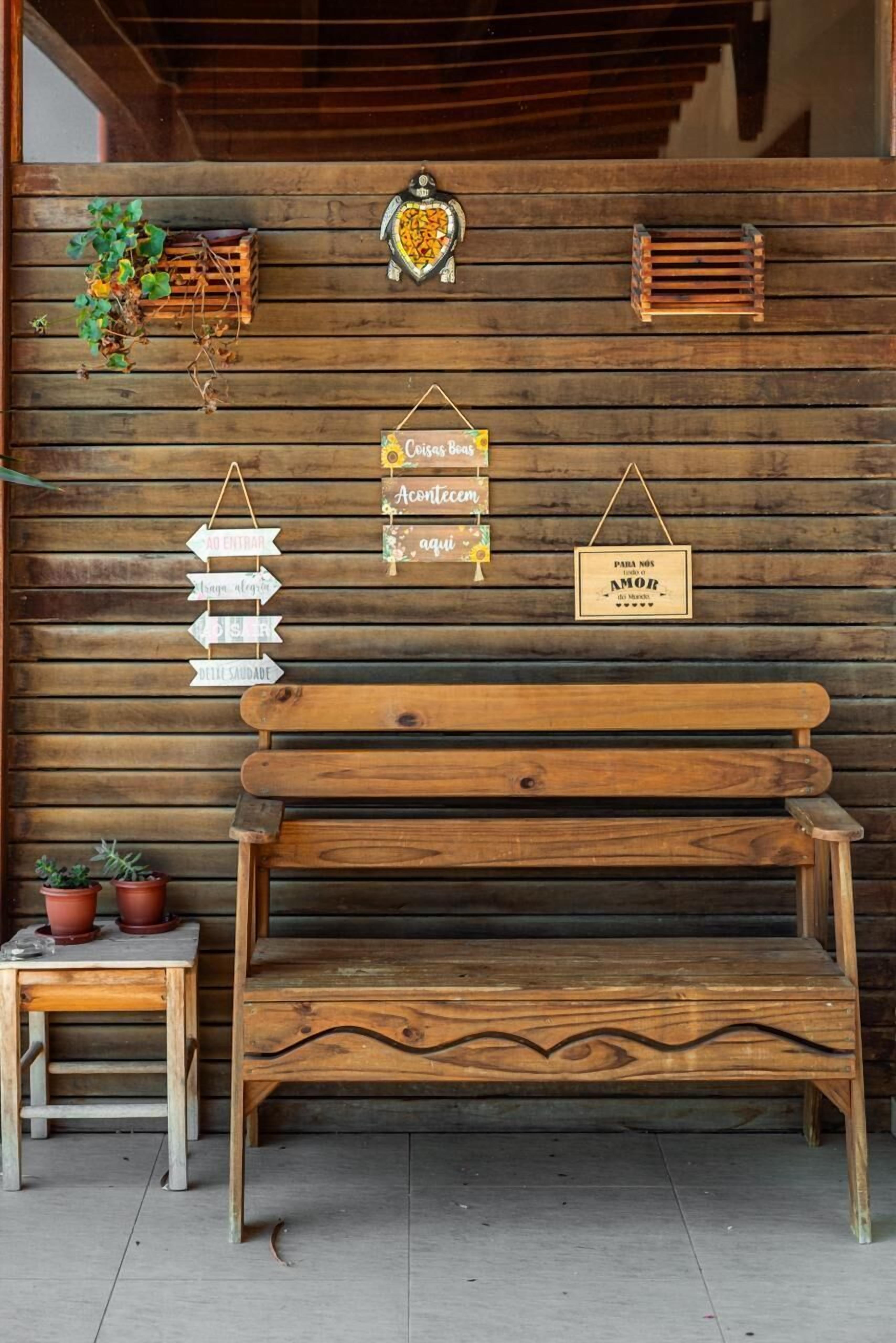 A wooden bench with a rustic design, a small table with potted plants, and decorative signs on a wooden wall.