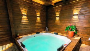 Un bain à remous dans un chalet en bois, avec des murs en bois et deux lampes fixées au mur.