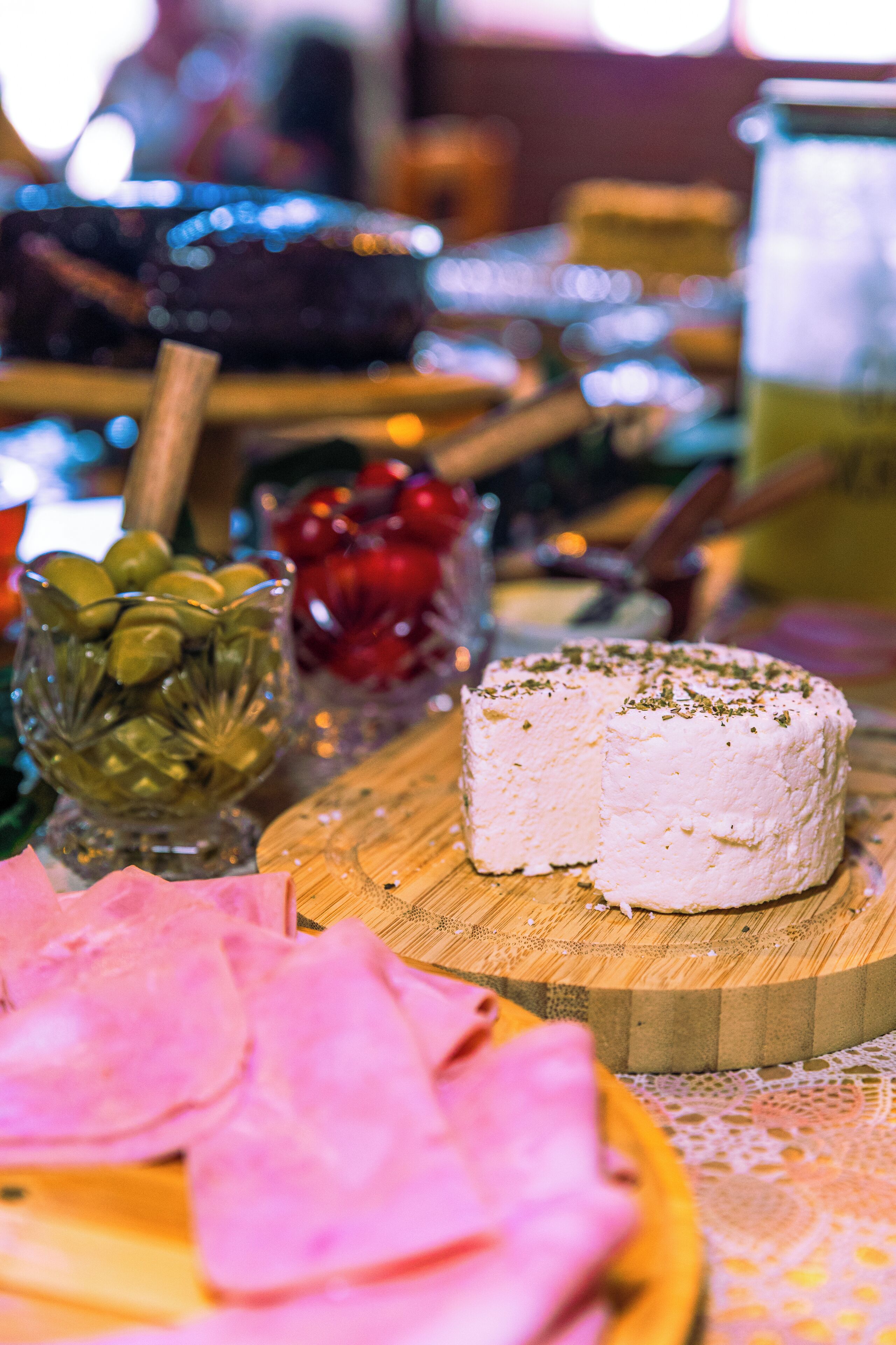 A cheese wheel on a wooden board, surrounded by various food items and decorations.