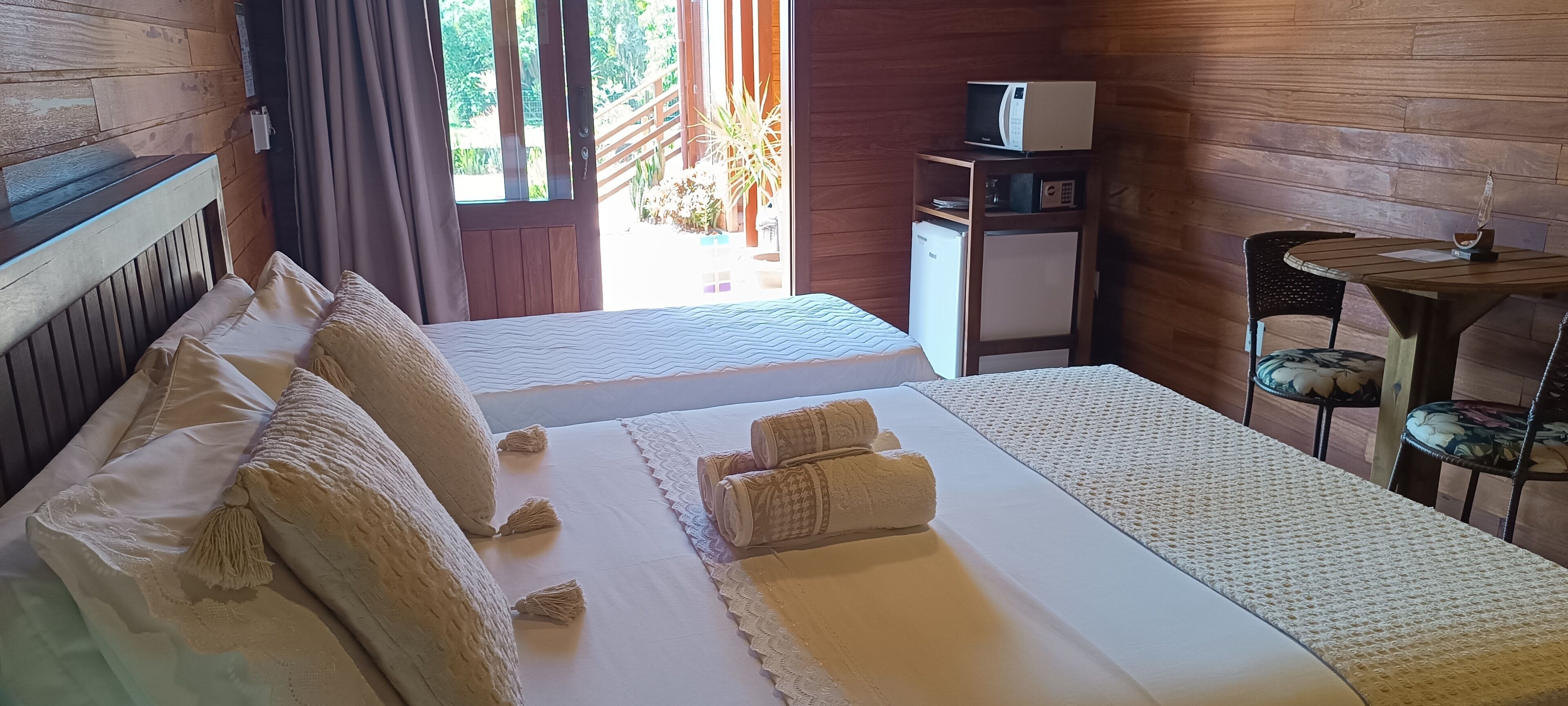 Habitación de hotel con dos camas, una mesita pequeña, microondas y vistas al exterior.
