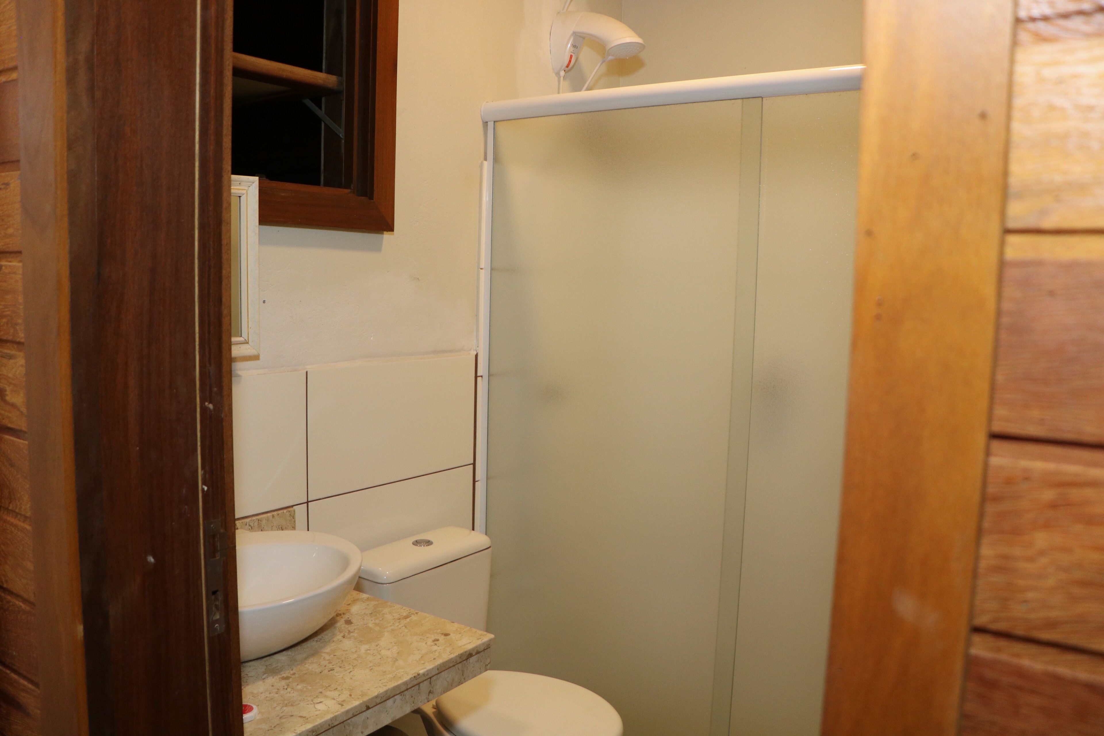 A small bathroom with a toilet, sink, and shower.