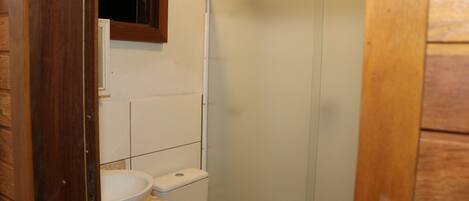 Une petite salle de bain avec des toilettes, un lavabo et une douche.