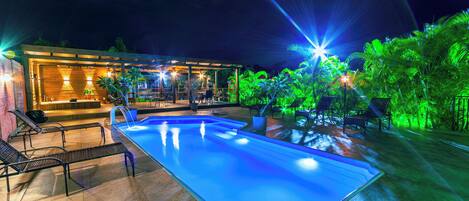 Una piscina al aire libre, sombrillas, sillones reclinables de piscina