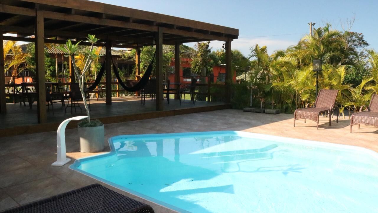 A pool area with a covered seating area, chairs, and a hammock.