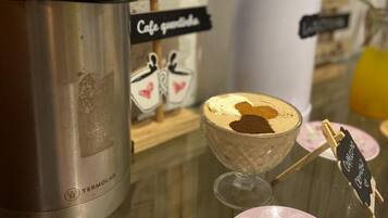 Una cafetera, un termo, un cartel que dice 'Café' y una taza de café sobre una mesa.