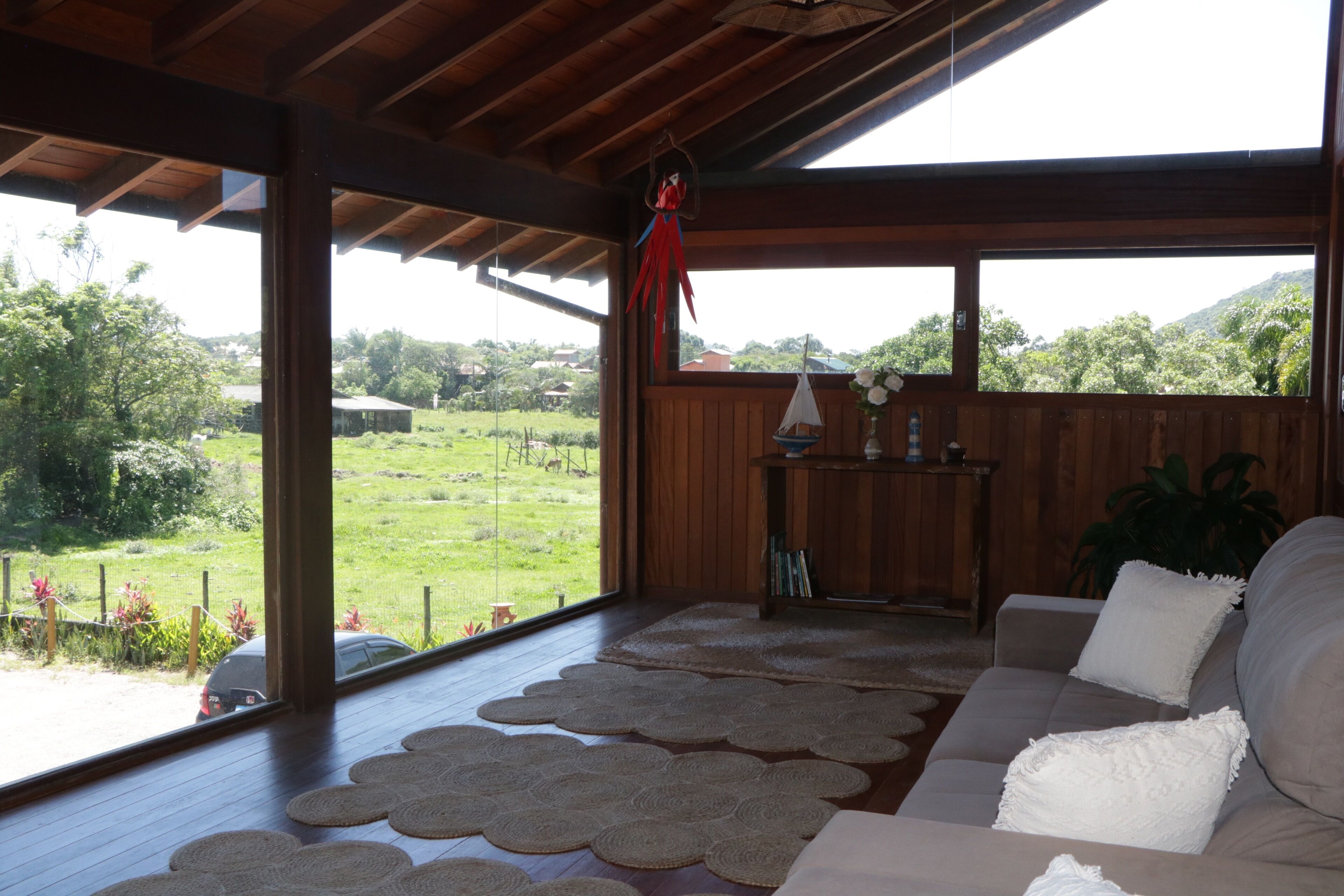 Habitació amb sostre de fusta, un sofà i vista a un paisatge verd.