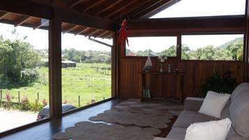 Habitació amb sostre de fusta, un sofà i vista a un paisatge verd.
