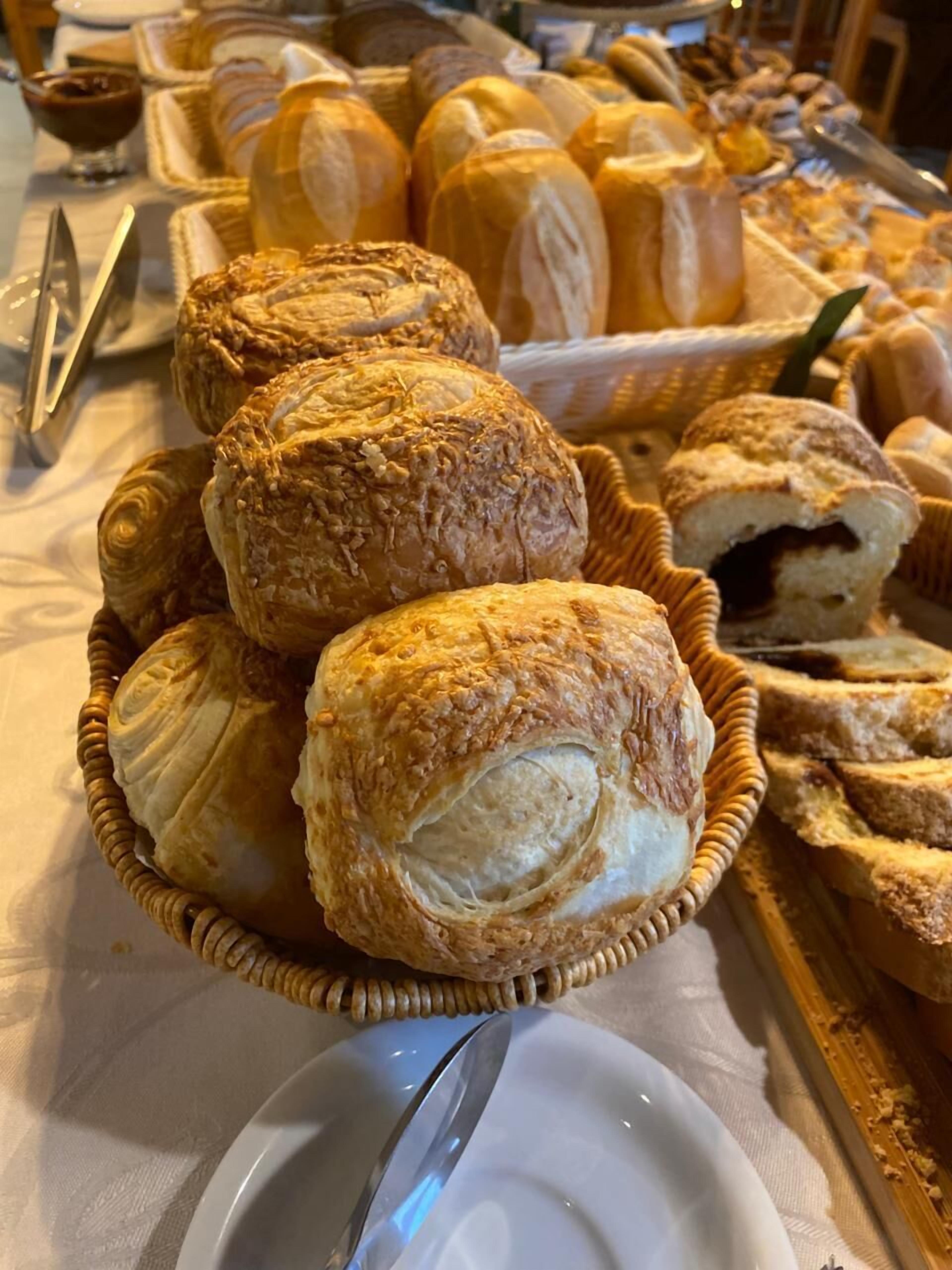 A table with various baked goods, including pastries and bread, arranged on a tablecloth.