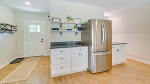 A modern kitchen with white cabinets, a stainless steel refrigerator, and a black countertop. - Cozy Ocala Retreat w/ Pool, Screened Lanai! (Ocala)