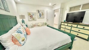 Un dormitorio con una cama grande, un aparador, un televisor y obras de arte en la pared.