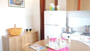 Eine kleine Küche mit einem weißen Kühlschrank, einem Herd und einem Holzschrank.