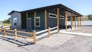 A small building with a covered porch and a gravel driveway.