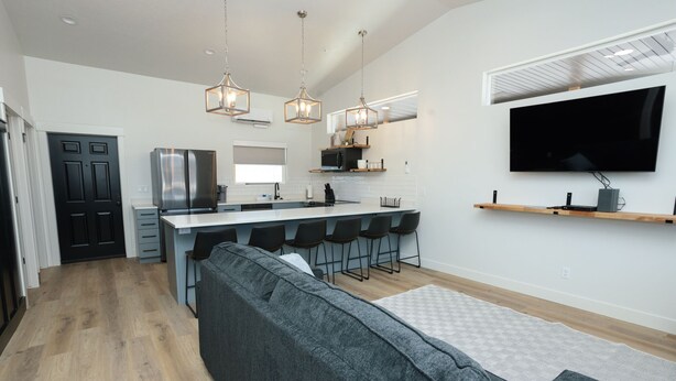 A modern kitchen with a central island, bar stools, and a flat-screen TV mounted above the island.