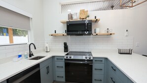 A modern kitchen with a built-in stove, microwave, and oven, light blue cabinets, and white countertops.