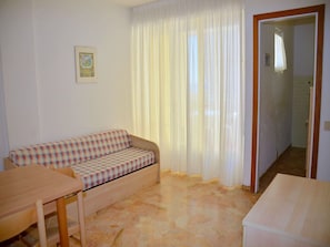 A room with a checkered sofa, a wooden table, and a door leading to another room.