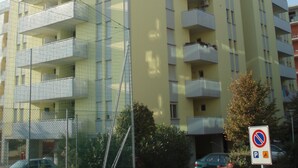 A multi-story building with balconies, a no parking sign, and a gated entrance.