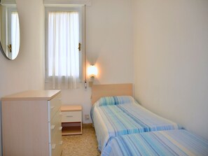 A bedroom with a bed, a dresser, a mirror, and a window with curtains.