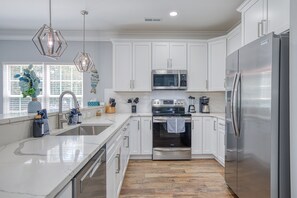 Enjoy cooking in this well-equipped kitchen with a large island, sink, and stainless steel appliances.