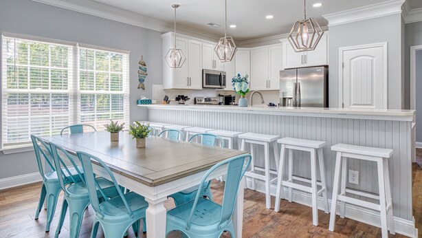 A kitchen with white cabinetry, a central island with stools, and pendant lighting. - Beach Home! Private Pool! Arcade-Beach-FUN! Elevator (Murrells Inlet)