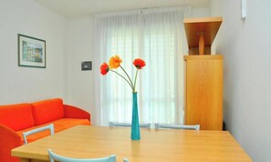 Ein Zimmer mit Holztisch, orangefarbenem Sofa und einem Blumenstrauß in einer Vase.
