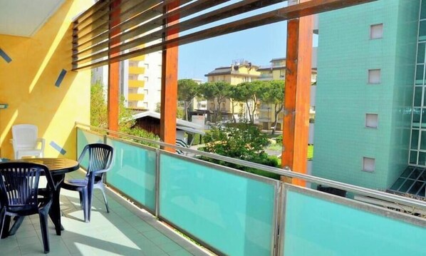 Ein Balkon mit Blick auf Gebäude, einem Tisch mit Stühlen und einer Brüstung.