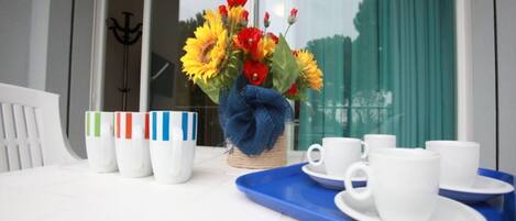 A table with a vase of sunflowers, white cups, and a blue tray.