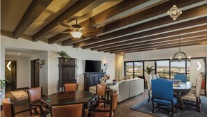 A spacious living area with a dining table, sofas, and a large window offering a view. - 2B vista encantada Cabo San Lucas (BCS)