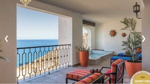A balcony with a view of the sea, a pool, and seating areas with potted plants. - 2B vista encantada Cabo San Lucas (BCS)