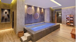 A modern spa room with a large hot tub, decorative wall art, and a wooden shelf with towels. - 2B vista encantada Cabo San Lucas (BCS)