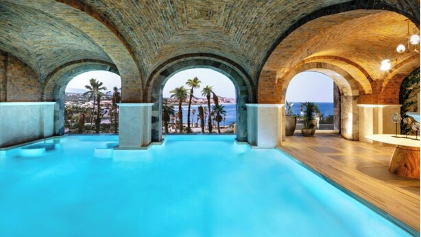 An indoor swimming pool with arched ceilings and views of palm trees and the sea. - 2B vista encantada Cabo San Lucas (BCS)