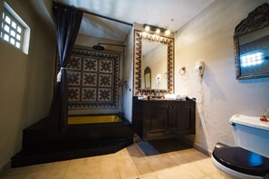 A bathroom with a shower, a sink, a toilet, and a mirror.