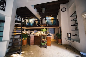 Cozy living space with a central kitchen, staircase, and decorative elements.