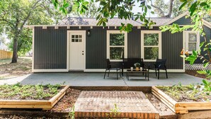 Ein kleines Haus mit Veranda, einem Ziegelweg und einem Garten.