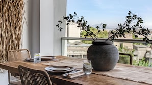 A dining table with a vase of greenery, plates, and glasses, set on a balcony with a view of buildings. - Sanders Old Port - Cozy 1-bdr. Apt. w/ Balcony (Thessaloniki)