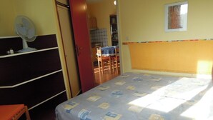 A bedroom with a bed, a dresser, a chair, and a fan. - One-bedroom Apartment Next to Bibione Thermae (San Michele al Tagliamento)