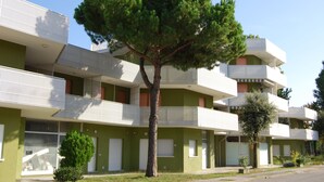 A multi-story building with balconies and a tree in front. - One-bedroom Apartment Next to Bibione Thermae (San Michele al Tagliamento)