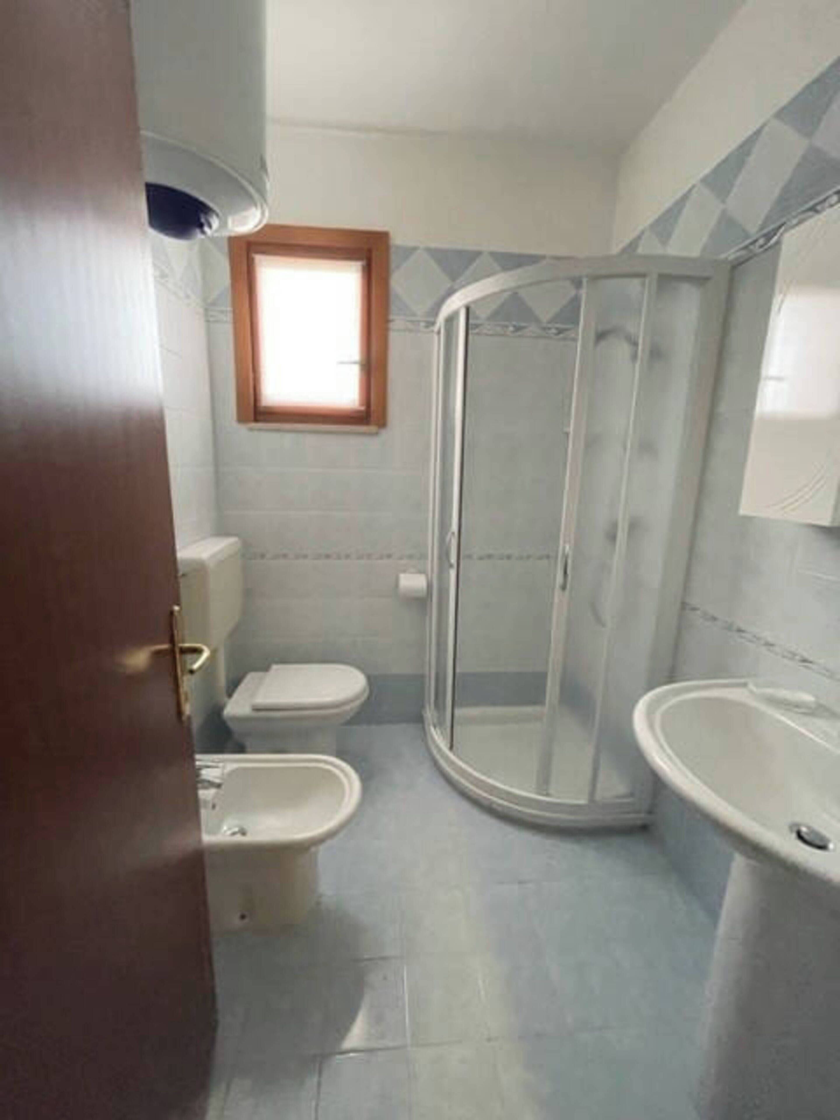 Een badkamer met toilet, bidet en douchecabine.